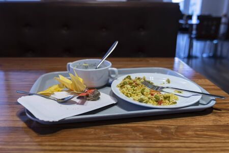 remnants of food on the tray, the remains of lunch. Rice with vegetables on a plate.
