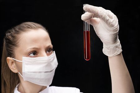 a test tube with a red substance or blood for analysis of the covid-19 coronavirus in the hands of a...