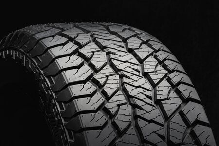 mud all-season tire with a powerful tread. Side view on a black background close up