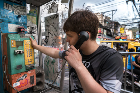Thailand, Phuket, April 15, 2020: guy talking on a street payphone, Thai street vibe on Bangla road,...