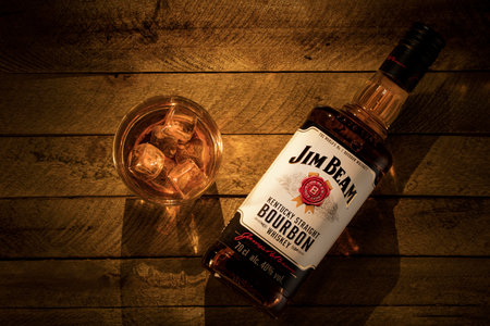 Russia, Krasnoyarsk, July 28, 2020: a bottle of Jim beam Bourbon from Kentucky and a glass of ice on a light brown wooden background.のeditorial素材