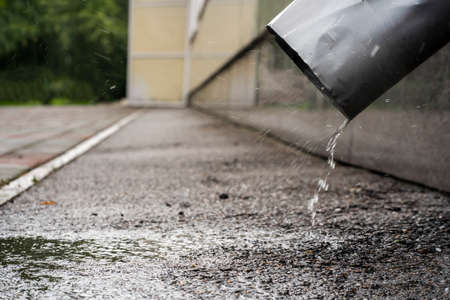 drain water through a pipe, raindrops, puddle and bad weather on the street. Illustration for the weather forecast.の写真素材