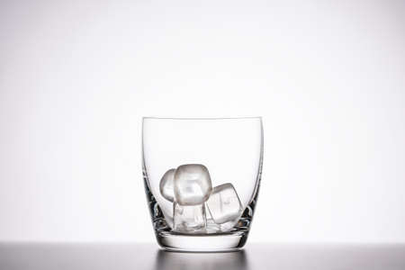 empty clear whiskey glass with ice on a white background.の写真素材