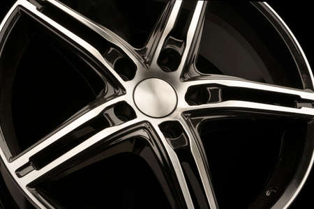 spokes of a black alloy wheel, close-up on a dark background