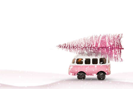 Toy bus car carries a Christmas tree from the forest. Pink and white colors, winter holiday new year moodの写真素材
