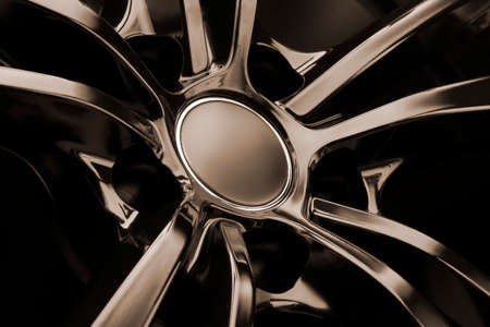 Black Gloss alloy wheel on a dark background. Stylish and expensive. mocap hub cap, reflection.