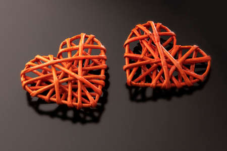 Two red braided hearts on a black background. Symbol of love, black color indicates sadness or...