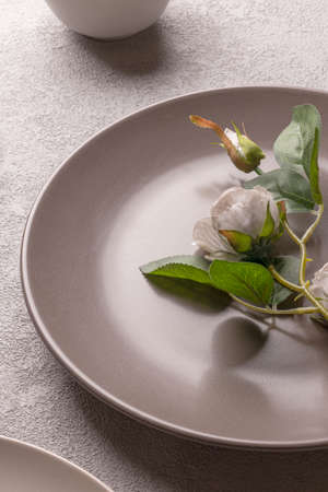 Rose in a plate on the table, gray pastel colors. Romantic minimalistic lifestyle still life. Vertical photo for a love storyの写真素材