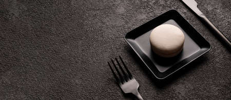 white macaroon cake in a square plate. stylish minimalistic food photography close-up. Black fork...