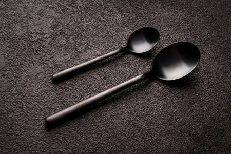 Spoons, teaspoons and regular ones, a couple. Theyre lying on a dark table. design for a restaurant or coffee shopの写真素材