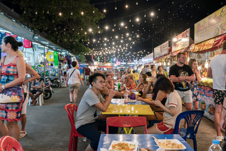 customers and tourists eat Thai food at the Phuket market at tables outside in the evening. Thailand, Phuket, December 30, 2019.のeditorial素材