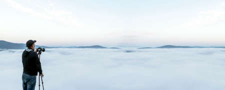 a man removes the fog on the camera. a traveler photographs a beautiful desert misty landscape in...