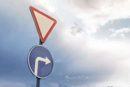 road sign sign attention and right turn on the background of dramatic sky and cloudsの写真素材