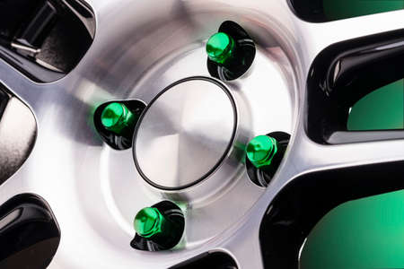 beautiful bright automotive wheel heptahedral nuts green close-up on a sporty style alloy wheel on a black background for auto tuning of a tire and disk store or auto parts gradient green backgroundの写真素材