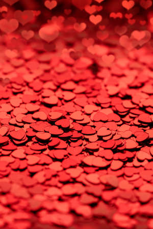 beautiful red empty textured background of confetti of shiny hearts. copyspace layout for a...