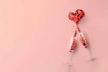 two glasses of champagne, a minimalist pink concept on the theme of love, a Valentines Day holiday or a wedding party. splash in the form of a heartの写真素材