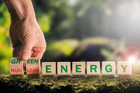 Nuclear or green energy symbol, The businessman turns over the cubes, and the concept of dangerous nuclear energy changes to a safe green one. European green taxonomy, the concept of green energyの写真素材