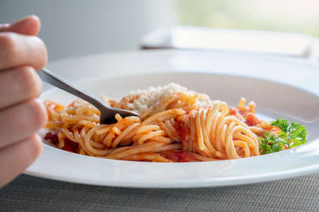 breakfast or lunch spaghetti. the girl is stringing pasta with a fork, a close-up of the plate....