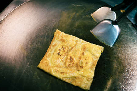 Cooking sweet Thai pancakes. an appetizing fried fresh crispy pancake with a banana in an envelope...