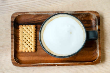 a black cappuccino coffee mug on a wooden tray. morning breakfast at the lifestyle coffee shop, top viewの写真素材