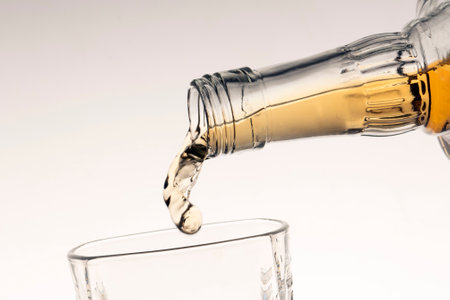 pouring bourbon whiskey into a glass from the neck of a bottle close-up white background gradientの写真素材