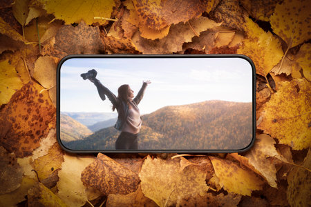 A young free woman in the mountains, on the screen of a mobile phone. she spread her arms out to the...