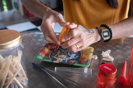 grinding of marijuana, the process of folding a joint of ganja with female hands in close-upの写真素材