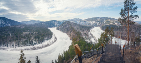 View of the Manskaya Loop in Krasnoyarsk. Winding frozen Mana river panorama, beautiful view of Siberian nature, mountains and cold sky. Early spring is waiting for an ice break.の写真素材