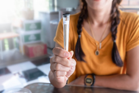 Cigarette joint with marijuana in a package close-up in a womans hand. Sale of medical cannabisの写真素材