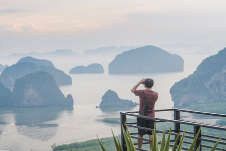 A photographer photographs a beautiful view from the Samet Nanghse observation deck in Thailand.Morning view of the blue mountains and stones in the water in Thailand, mysterious beauty. Tourism travel and landscape photography.の写真素材
