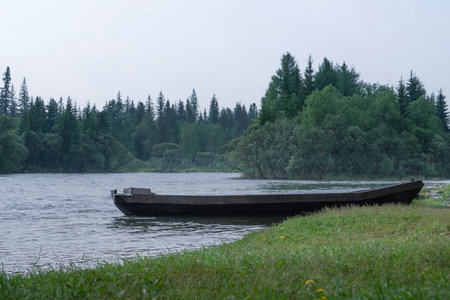An old wooden boat on the river bank, in the middle of the forest in the morningの写真素材