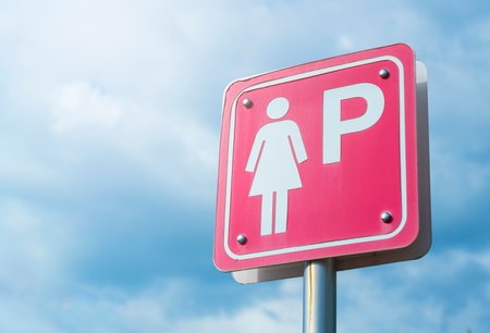 Red female parking sign against a blue sky.の写真素材