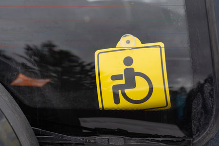 Representation of a yellow wheelchair accessibility sign displayed on a car windowの写真素材