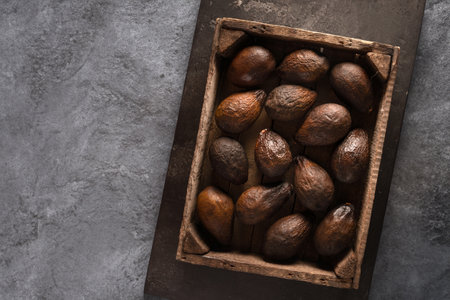 Top view of an old brown avocado in a wooden box. The concept of aging, storage and spoilage of fruits, as well as a beautiful textured background.の写真素材