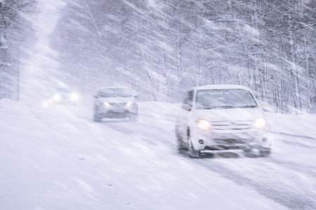 Winter snowstorm, snowfall and ice on roads with strong winds. Poor visibility and dangers on the road, driving safety in winter in bad weather. Cars Navigating Through Heavy Snowstorm Conditions That Create Unique Winter Adventuresの写真素材