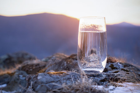 Pure natural drinking soda mineral water in a glass at the top of the mountain in winter. The frosty...