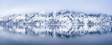 A Picturesque Winter Landscape of SnowCovered Mountains and a Calm Lake Reflection at Dusk, Snow-capped mountains with pine trees, reflection in the Yenisei river, beautiful winter background.の写真素材
