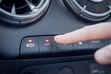 Car Interior Climate Control System Featuring Air Conditioning Control Buttons for Comfort. A closeup view of a finger operating the controls for the cars air conditioning system and air ventsの写真素材