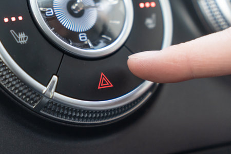 Car Interior Controls Activating the Hazard Lights for Enhanced Safety and Alertness. a closeup of a car dashboard where a finger is pressing the hazard light buttonの写真素材