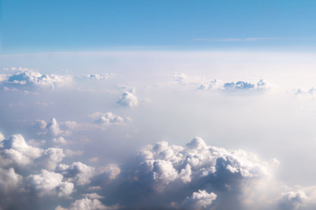 Background beautiful white dramatic clouds in a blue sky. Top view from an airplane. Fantastically...