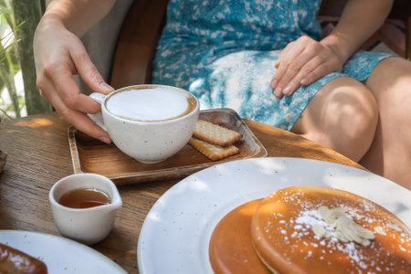 Breakfast with pancakes. A woman drinks her morning coffee in a sunny outdoor cafe. There is a...