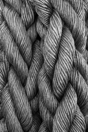 A close-up perspective reveals the intricate details of multiple gray ropes woven together, creating...