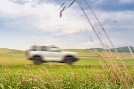 The concept of road trips and excursions in nature auto tourism. White SUV drives quickly along a...
