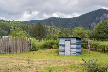 Rustic old outdoor toilet blue house on the background of beautiful nature and mountains. Small...
