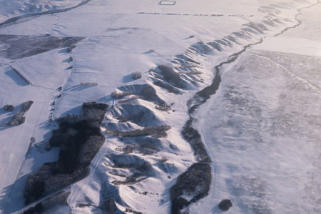 Aerial view shows a vast, pristine snowcovered landscape with hills and a winding river. Mountainous hilly snow-covered ridge imho aerial view. Minino, Krasnoyarskの写真素材