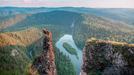Breathtaking view from the cliff over the winding river surrounded by lush forests and rolling mountains. A serene and untouched natural landscape.の写真素材