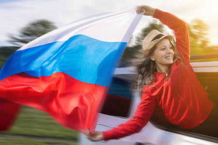 Woman celebrating Russian Independence Day while traveling in a car, waving the Russian flag during a summer trip. Independence Day or Constitution Day of Russia and tourism Russian travelの写真素材