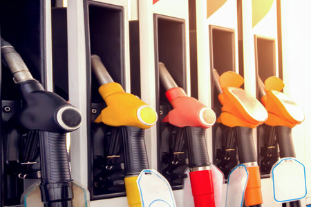 Gas station refueling guns ready for customers to fill up with gasoline or diesel fuel during daytime.の写真素材