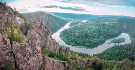 Rocks and the Mana River, the nature of the Siberian taiga. Breathtaking view from a cliff overlooking a winding river and lush green forests during the golden hour in a remote landscapeの写真素材