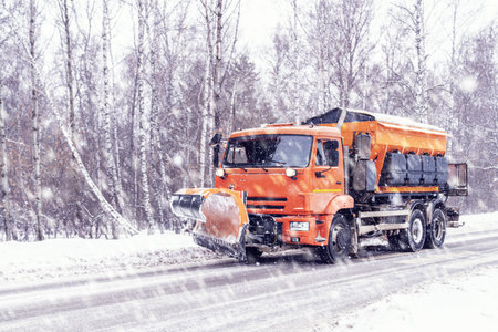 Snow removal equipment clears icy country roads during heavy winter snowfall